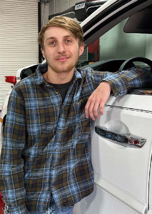   Parker Clardy leans into the open, driver-side window of a car.